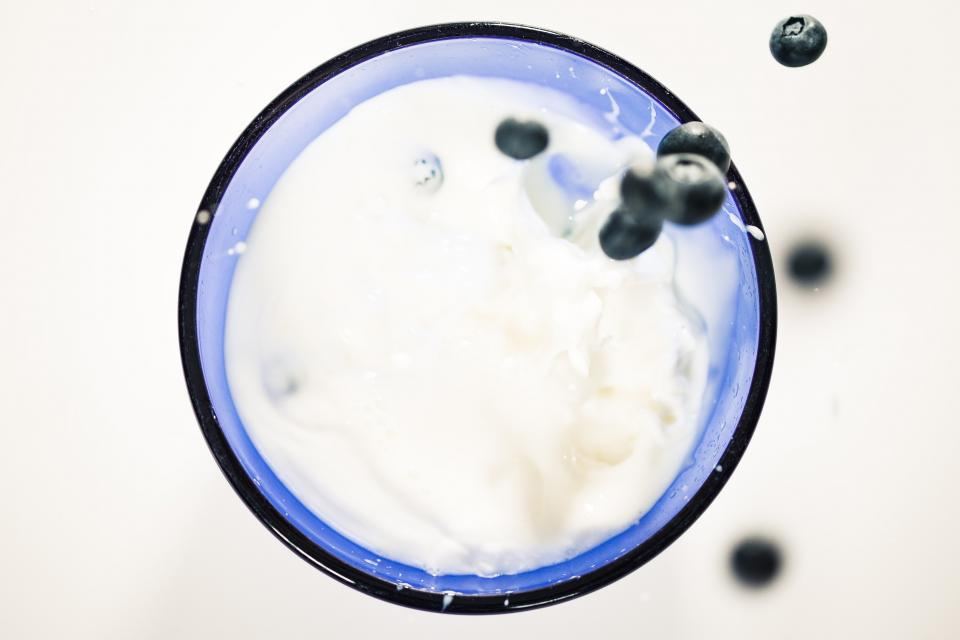 Glas Milch von oben mit Heidelbeeren, die hineinfallen